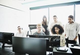 Group of people sat around computer talking