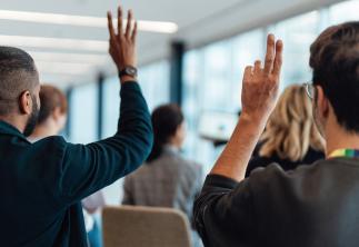 People in meeting with their hands up