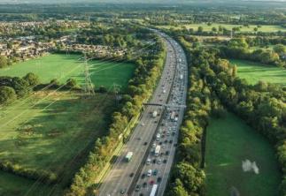Contrast of motorway in the middle of image and green fields both sides