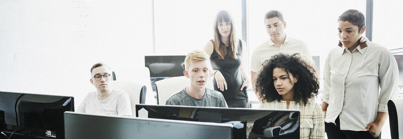 Group of people sat around computer talking