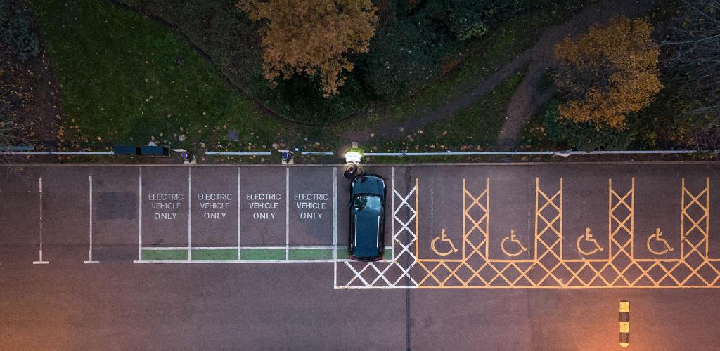 Ariel image of car park and person putting their EV car on charge