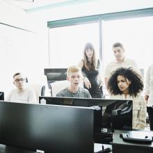 Group of people sat around computer talking