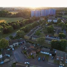 Landscape showing green field and trees with houses and tower flats-GettyImages-1407388421