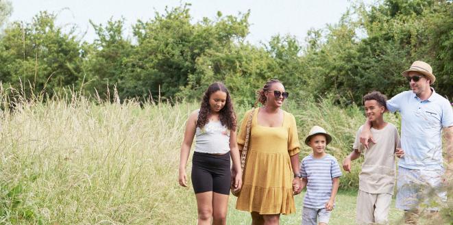 Family walking in summer outfits in a field