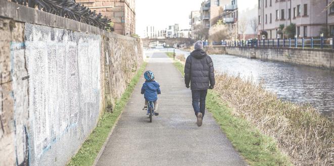 Man walking with child riding bike