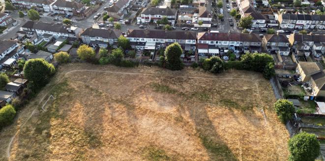 brown grassy football field surrounded by houses