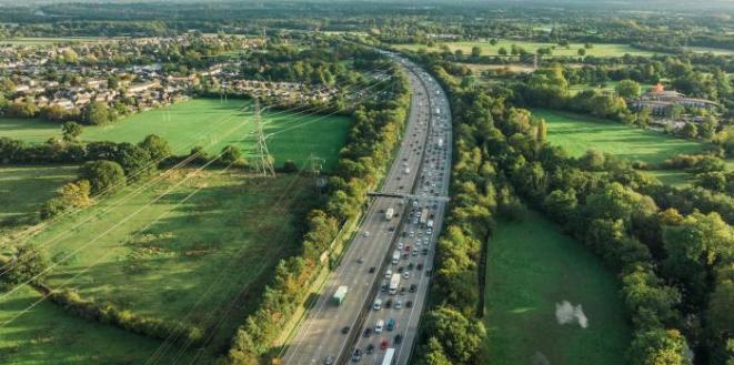 Contrast of motorway in the middle of image and green fields both sides