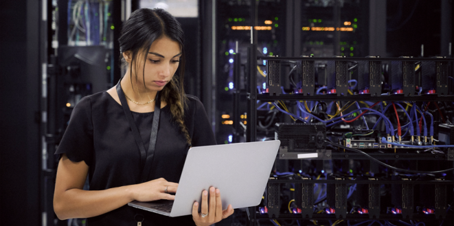 Person holding a laptop in front of computer equipment