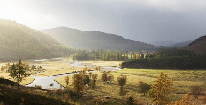 A scenic landscape featuring a winding river flowing through a wide, open valley. 